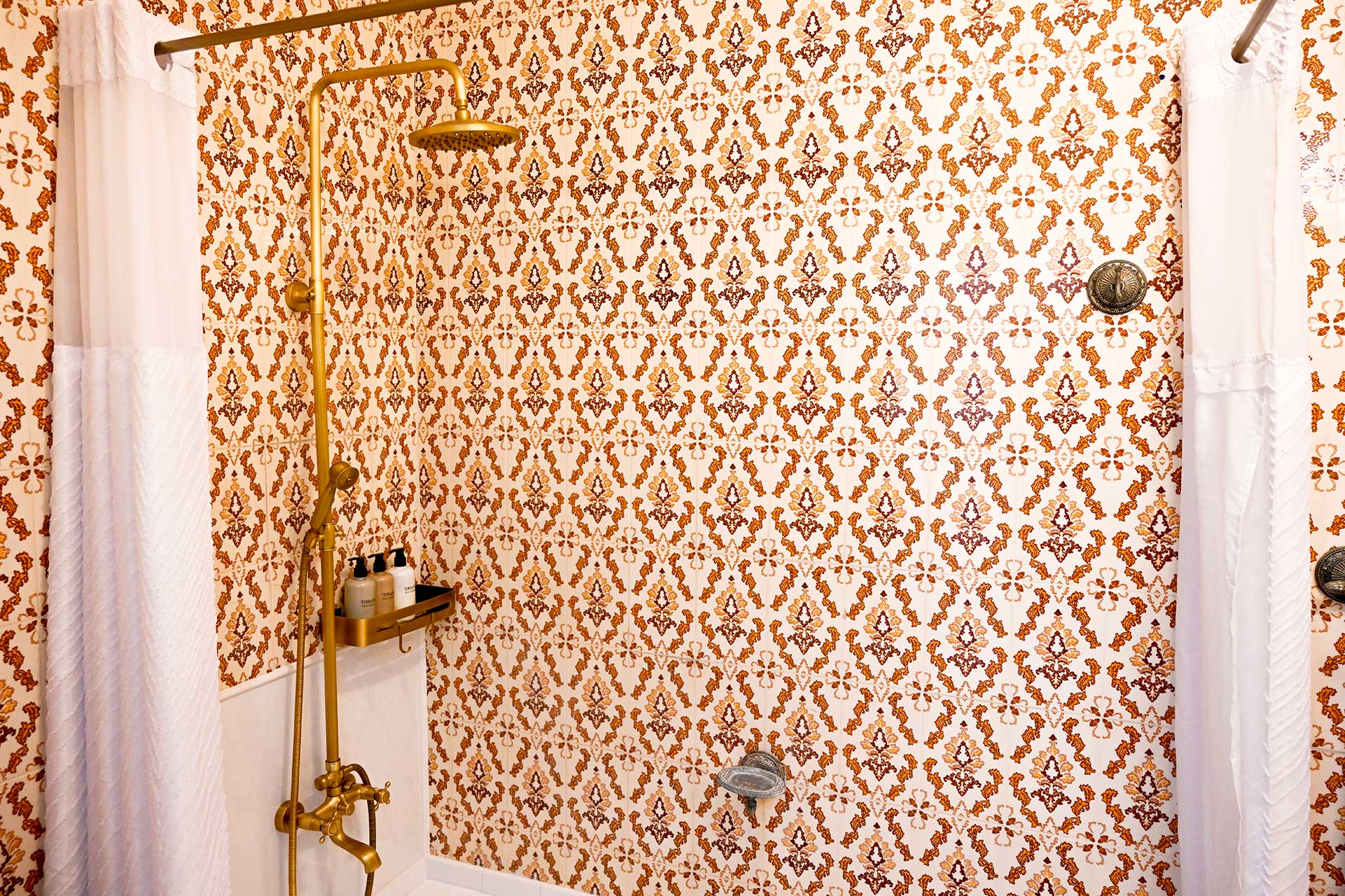 Vintage-style rain shower with gold fixtures and patterned tiles and eco-friendly toiletries at Hacienda Eterna Primavera
