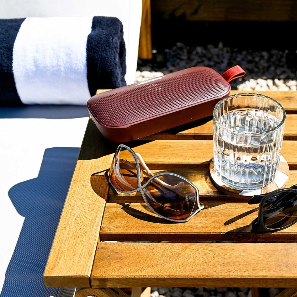 Relaxing sun lounge scene with sunglasses, a glass of water, a portable speaker, and a rolled towel in the private garden at Hacienda Eterna Primavera.