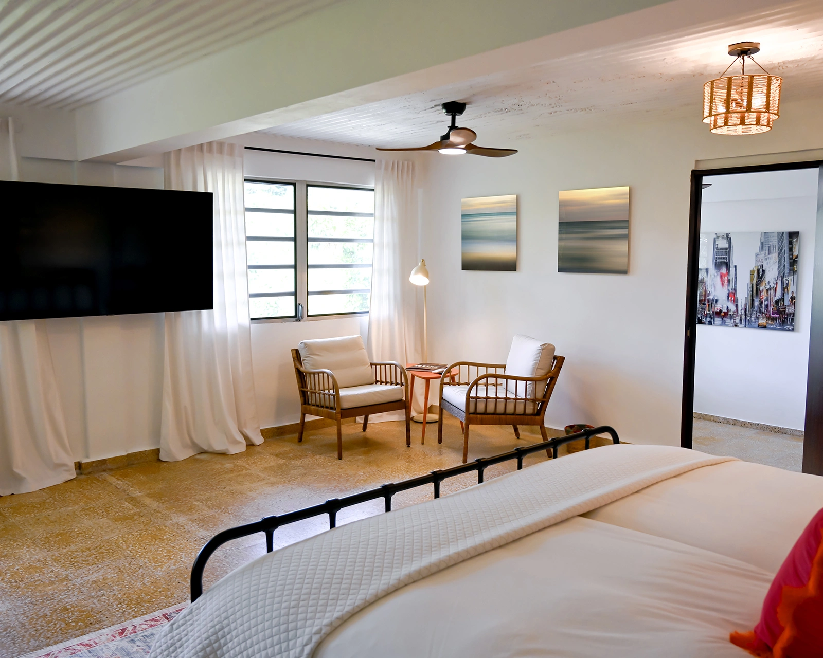 Spacious master bedroom at Hacienda Eterna Primavera in Puerto Rico with king bed, seating area, smart TV, and natural light