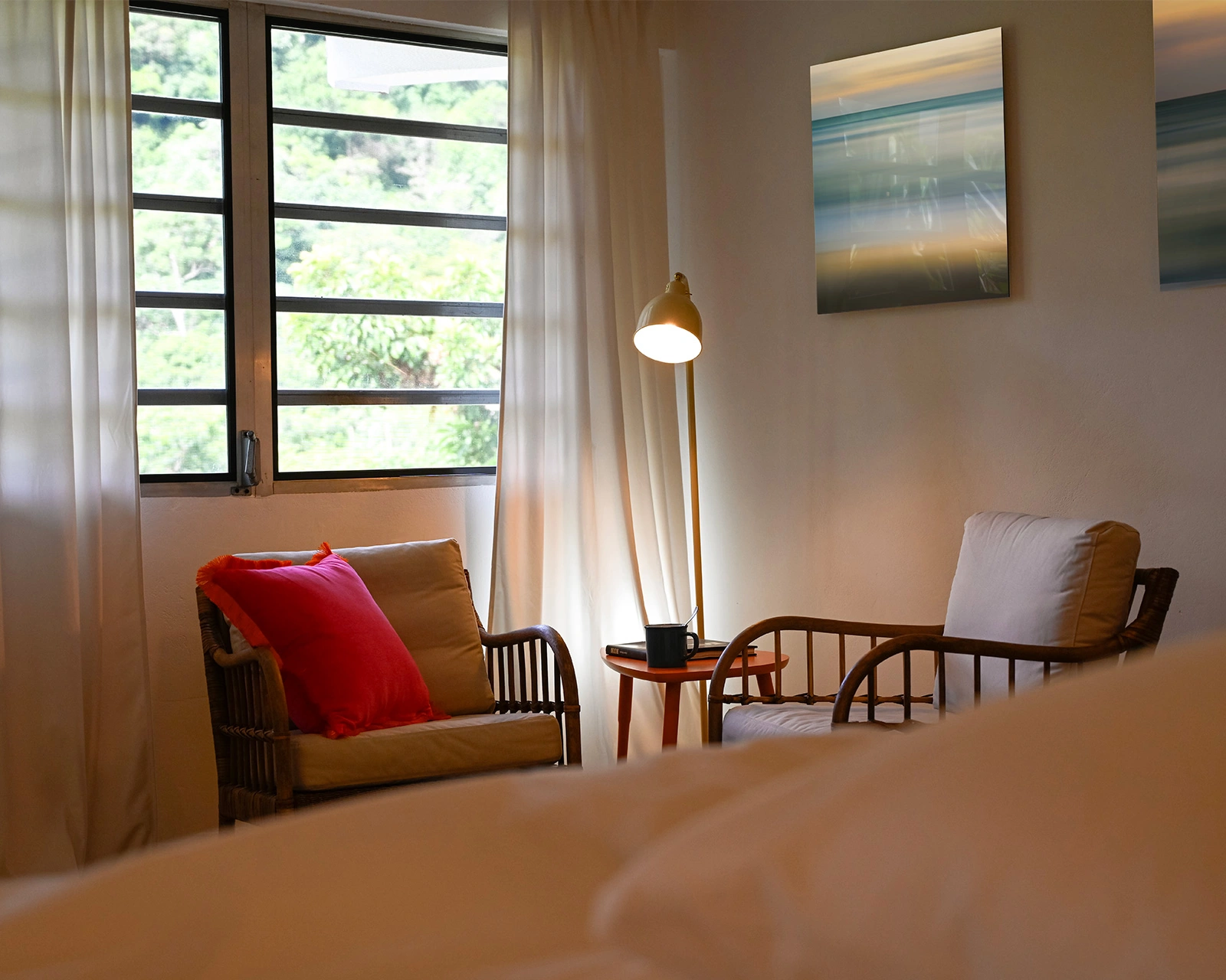 Cozy reading corner in the master bedroom at Hacienda Eterna Primavera with armchair, lamp, and mountain view window in Puerto Rico