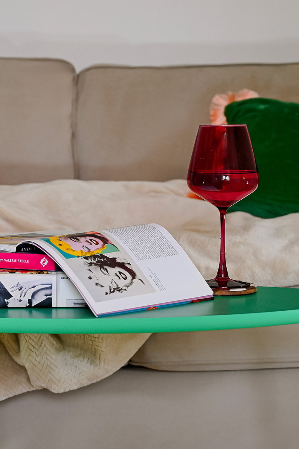 Open art book and red wine glass on a green coffee table in the living room