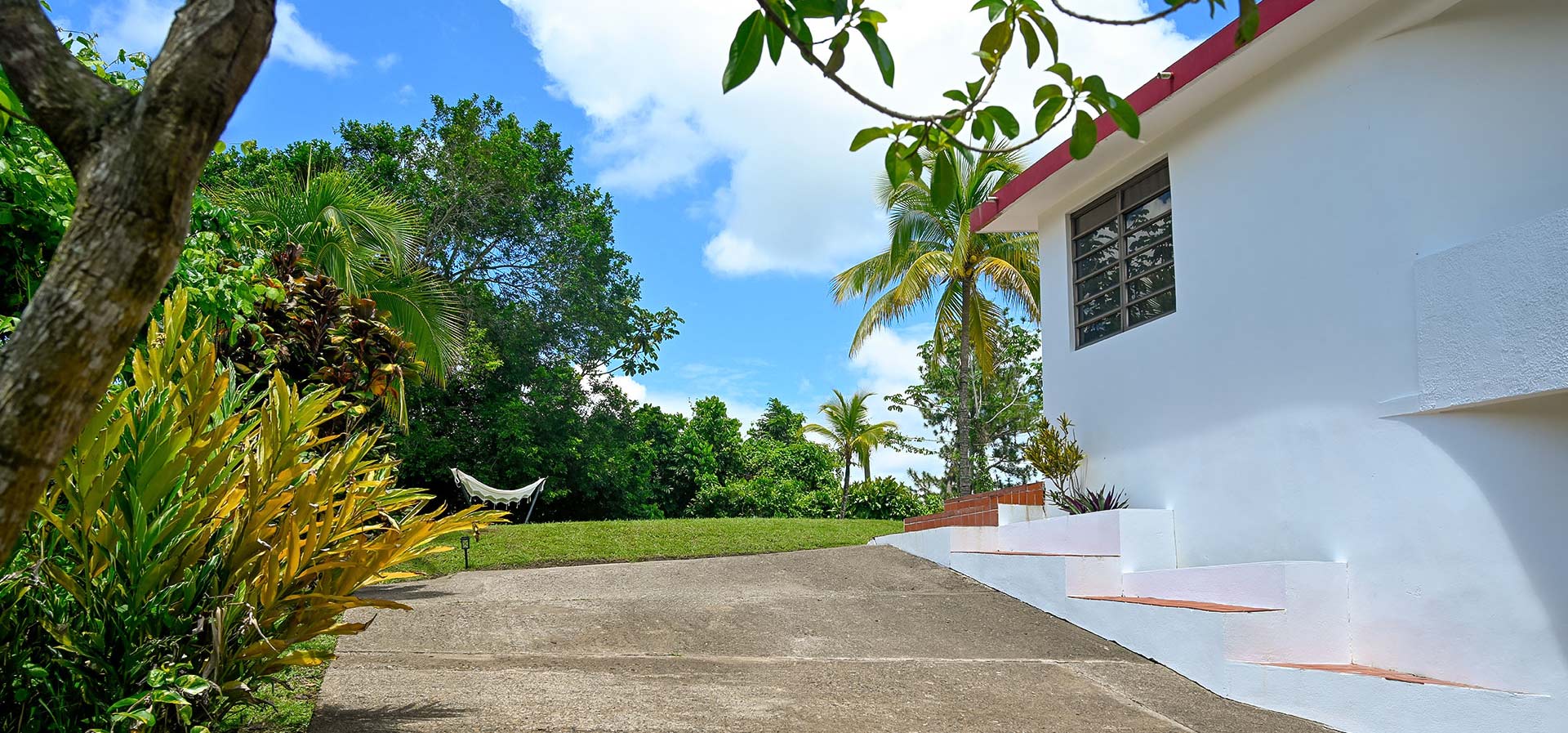 Main house exterior and driveway surrounded by tropical greenery at Hacienda Eterna Primavera in Puerto Rico.