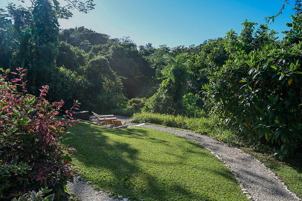 Garden path leading through tropical greenery at Hacienda Eterna Primavera, surrounded by mountain landscape