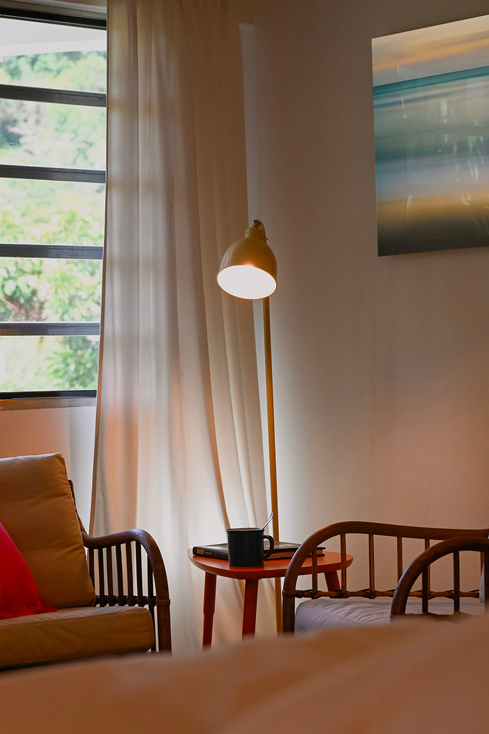 Cozy interior corner at Hacienda Eterna Primavera with reading chairs, floor lamp, and morning light through window in Puerto Rico mountain retreat