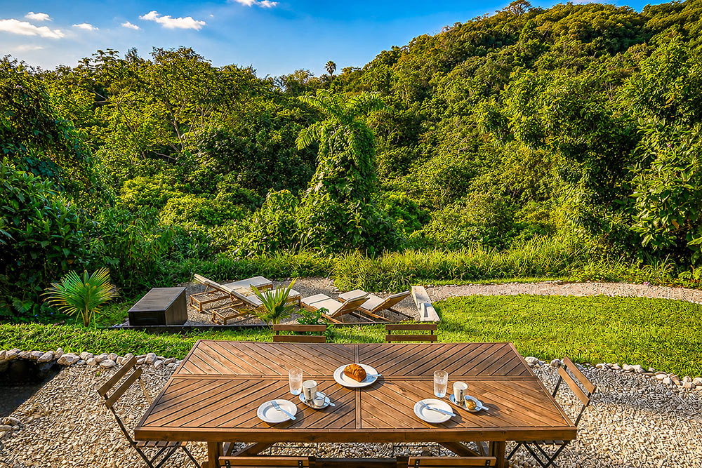 Outdoor dining area overlooking a private tropical garden and mountain landscape at Hacienda Eterna Primavera in Puerto Rico.